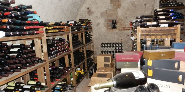 La cantina con la volta in pietra, le scaffalature di bottiglie e le casse di Champagne