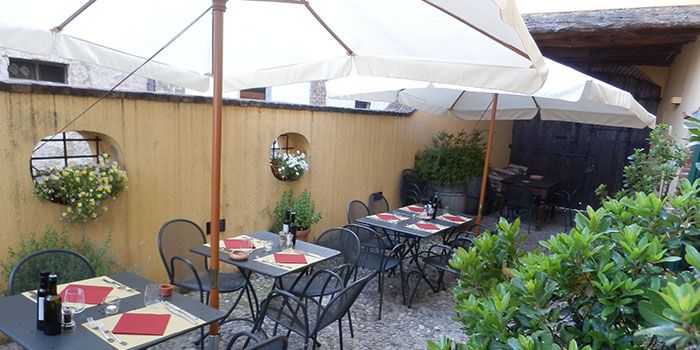 Il cortile con gli ombrelloni bianchi e i tavoli all'aperto