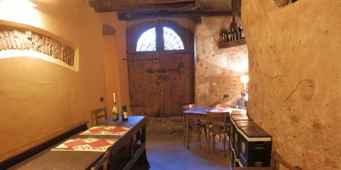 Una saletta con i muri antichi e una vecchia porta di legno ad arco con la lunetta