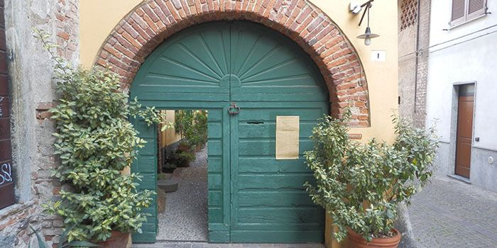 La porta verde ad arco su vicolo Carrera, di giorno, con due vasi di piante