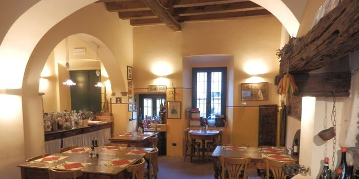 La sala con gli archi bianchi, i tavoli apparecchiati e il camino